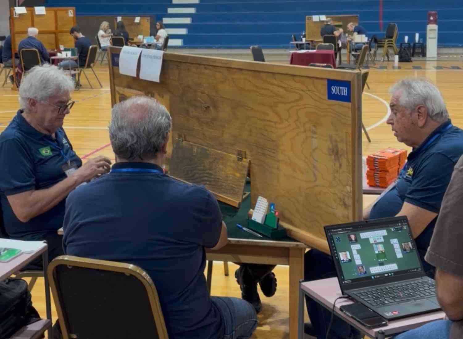 Group of seniors playing a bridge card game together at a table.